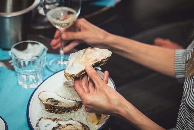 <p>A woman eats an oyster at a seafood restaurant. Molluscs are dying off in huge numbers along the East Coast and in the Gulf of Mexico </p>