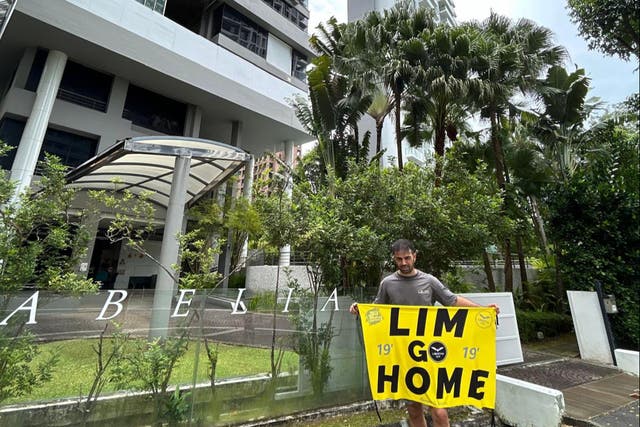 <p>Dani Cueta shared his picture holding a banner reading ‘Lim Go Home’ outside what is believed to be billionaire Peter Lim’s house in Singapore </p>