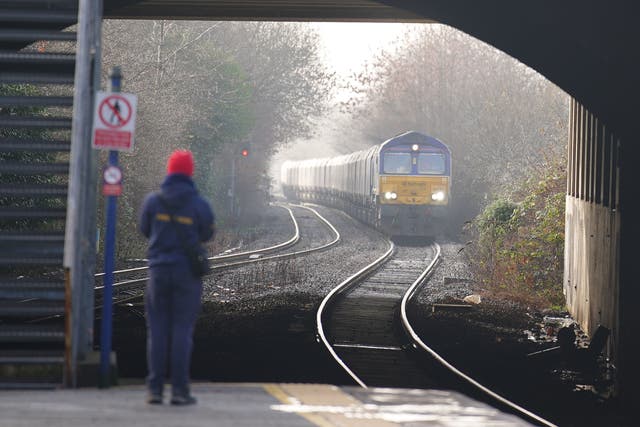 <p>A passenger waits for a train at Denton railway station in Greater Manchester</p>