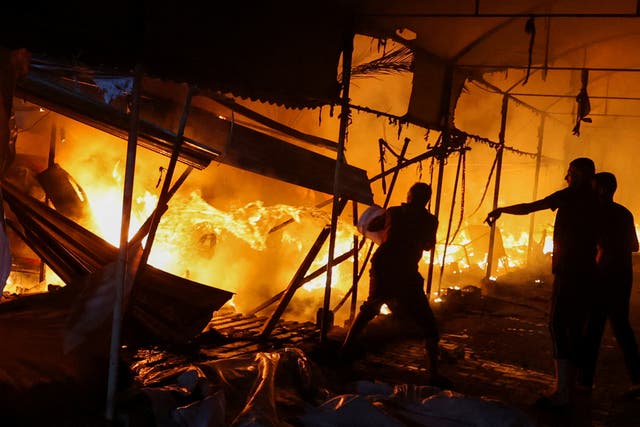 <p>Three men attempt to extinguish a fire after an Israeli airstrike on tents sheltering displaced people</p>